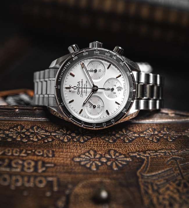 Omega Speedmaster 38 with a silver dial and steel bracelet, on a tooled leather book cover