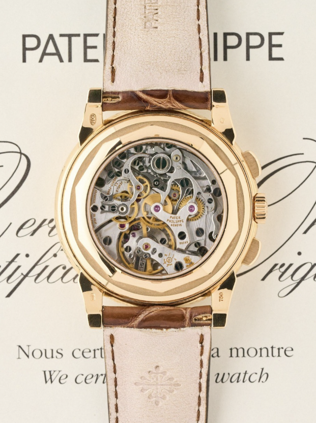 Caseback of the Patek Philippe 5970, its chronograph movement open over the certificate of origin